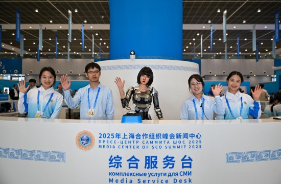 8月28日,可進行中、俄、英語互動的人形機器人“小合”與志愿者服務人員在綜合服務臺歡迎到訪記者。新華社記者 孫凡越 攝